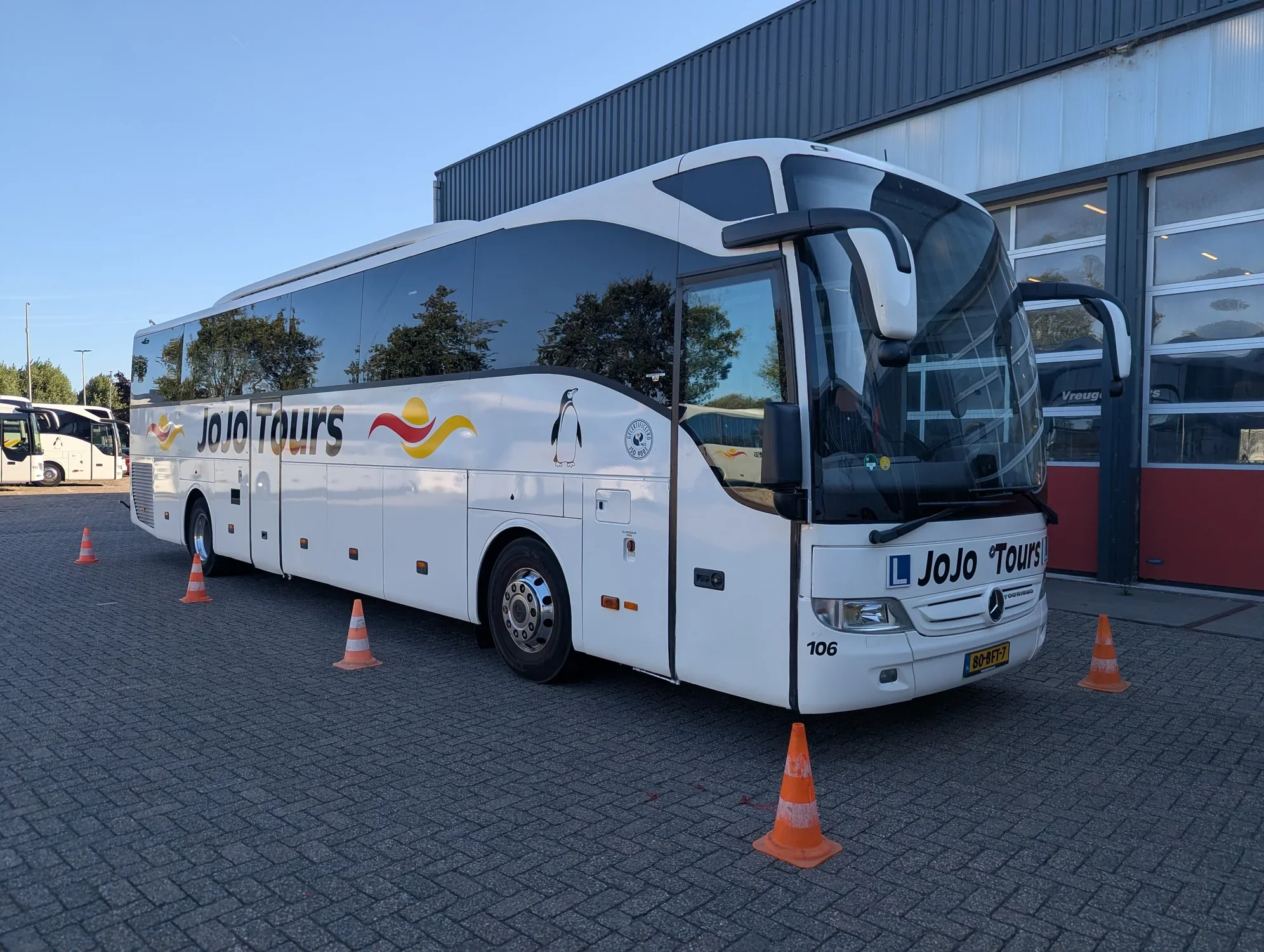 Lesbus van JoJo Tours met pionnen op het oefenterrein